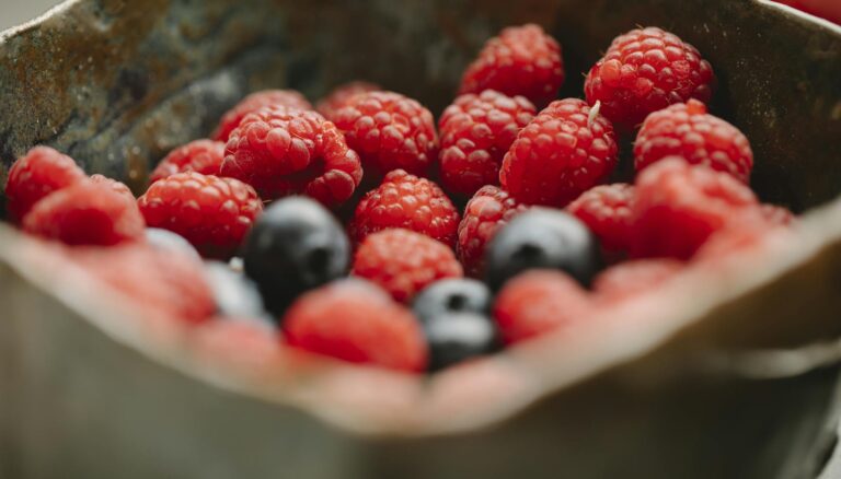 Appetizing ripe raspberries and blueberries in bowl