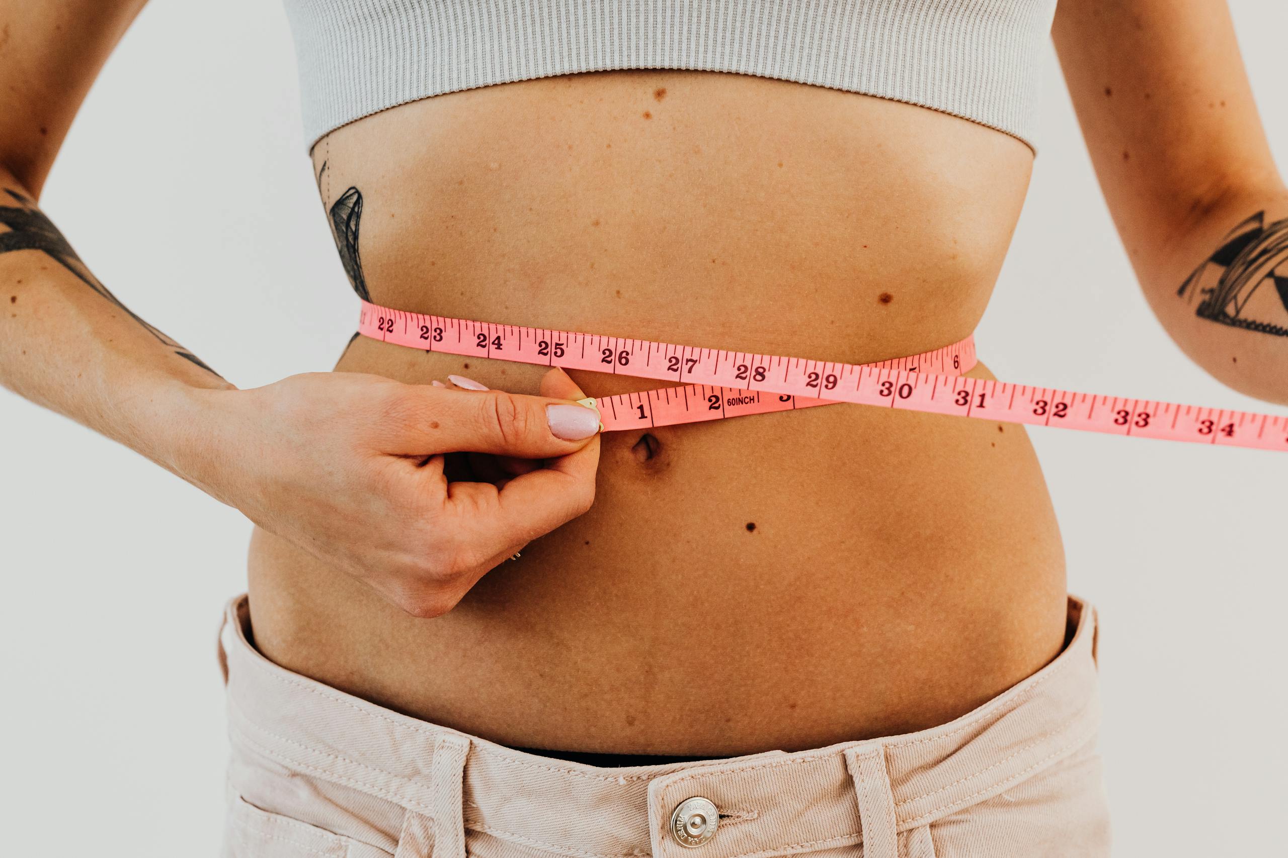 a woman measuring her waist showing the results she has gotten with semaglutide weight loss shots phoenix